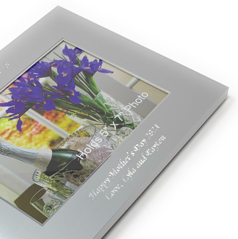 May include: Silver photo frame with a 5x7 inch photo opening. The frame has an engraved message that reads "Happy Mother's Day 2021 Love, Lyla and Cayton".