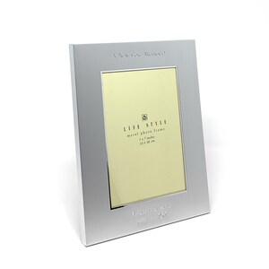 May include: A silver metal photo frame with a 5x7 inch opening. The frame has the text "A New Core Memory" and "LIFE STYLE metal photo frame 5x7 inches 13x18 cm" engraved on the front. The frame is personalised with the text "Mikasa & Rose July 4, 2021".