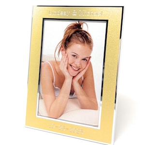 May include: A gold-colored picture frame with a silver border. The frame holds a photo of a smiling woman. The text "Lindsay & Michael" is at the top, and "10-25-2025" is at the bottom.