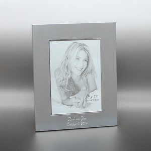 May include: Silver picture frame with a 5x7 inch (13cm x 18cm) opening. The frame has a personalised inscription that reads "Josh and Jess October 13, 2014".
