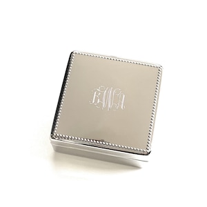 May include: A silver square box with a beaded border and a monogrammed initial "KWH" on the front.