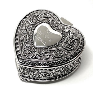 May include: Silver heart-shaped trinket box with an ornate design and a hinged lid. The lid features an engraved heart with the inscription "For my love Amata".