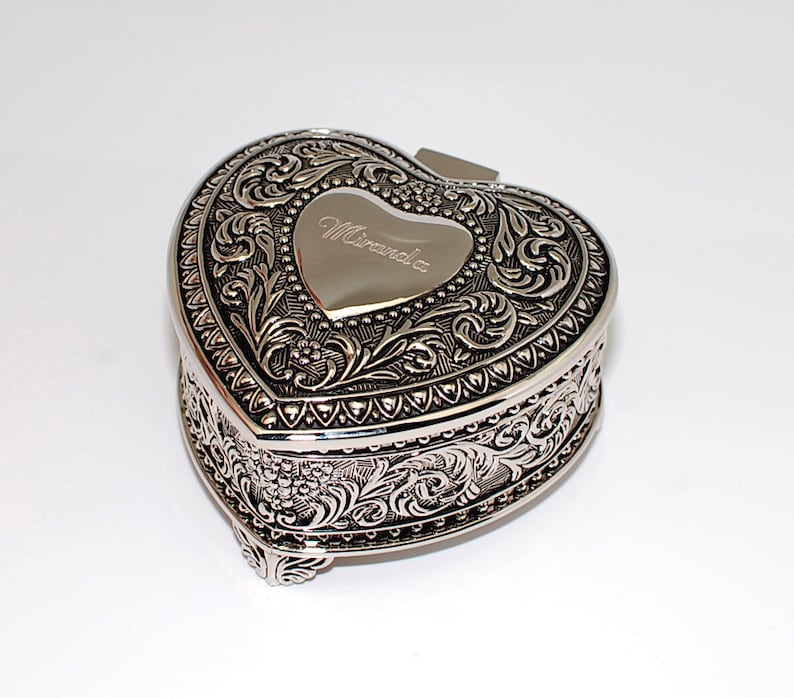 May include: Silver heart-shaped trinket box with an ornate floral design and the name "Miranda" engraved on the lid.