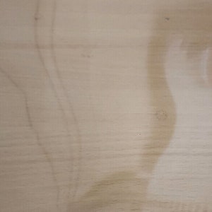 May include: A close-up of a light brown wood surface with a faint, light brown stain.