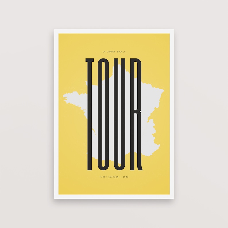 Peut inclure: Une affiche jaune avec un contour blanc de la France et le mot "TOUR" en lettres noires. Le texte "LA GRANDE BOUCLE" est en haut et "FIRST EDITION - 1903" est en bas.
