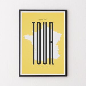Peut inclure: Une affiche jaune avec un cadre noir repr&eacute;sentant un contour blanc de la France avec le mot "TOUR" en grandes lettres noires. Le texte "LA GRANDE BOUCLE" est au-dessus du mot "TOUR" et le texte "#FIRST EDITION - 1903" est en dessous du mot "TOUR".