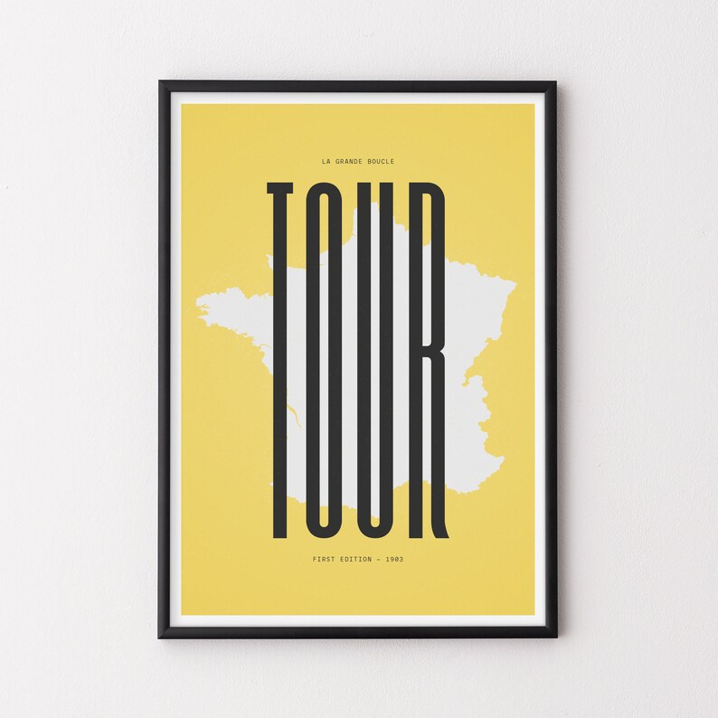 Peut inclure: Une affiche jaune avec un cadre noir repr&eacute;sentant un contour blanc de la France avec le mot "TOUR" en grandes lettres noires. Le texte "LA GRANDE BOUCLE" est au-dessus du mot "TOUR" et le texte "#FIRST EDITION - 1903" est en dessous du mot "TOUR".