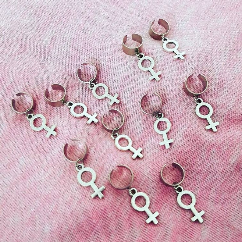 Puede incluir: Diez pinzas para el pelo plateadas con un colgante en forma de s&iacute;mbolo femenino. Las pinzas est&aacute;n dise&ntilde;adas para sujetar el pelo.