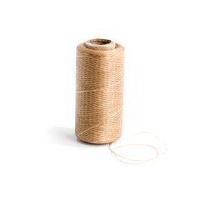 May include: A spool of brown waxed thread with a length of thread extending from the spool.