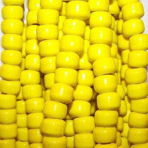 May include: A close-up of a large quantity of bright yellow round beads. The beads are arranged in rows and are all the same size and shape.