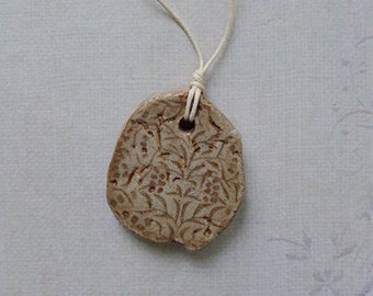 Asymmetrical beige ceramic handmade pendant, necklace with imprint.
