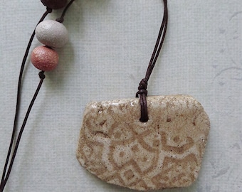 Beige ceramic handmade pendant, necklace with imprint.