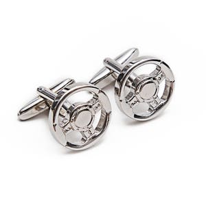May include: A pair of silver cufflinks with a steering wheel design.
