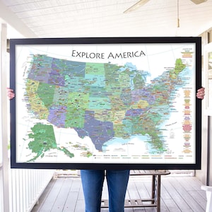 May include: A person holding a large framed map of the United States with the title "Explore America". The map is detailed and colorful, showing state borders, major cities, and geographical features.