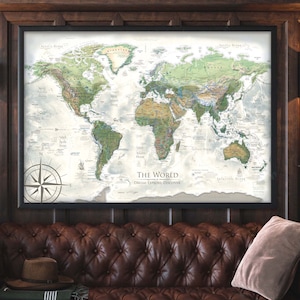 May include: A framed world map with a compass in the bottom left corner. The map is in a vintage style with a white background and green and brown landmasses. The text "The World Dream Explore Discover" is printed at the bottom of the map.