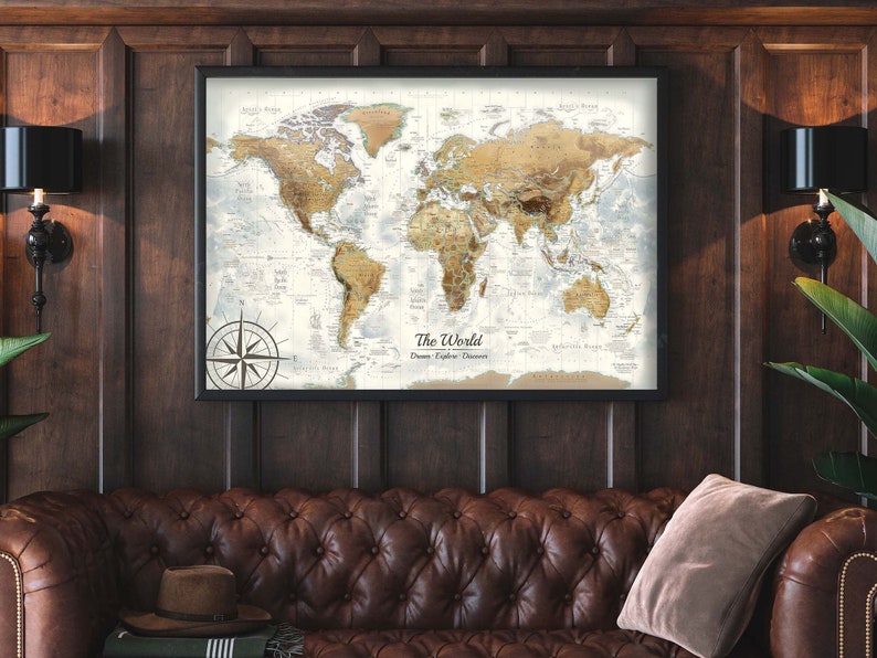 Puede incluir: Un mapa del mundo enmarcado con una rosa de los vientos en la esquina inferior izquierda. El mapa es de estilo vintage con una combinaci&oacute;n de colores marr&oacute;n y beige. El mapa est&aacute; colgado en una pared de madera oscura.