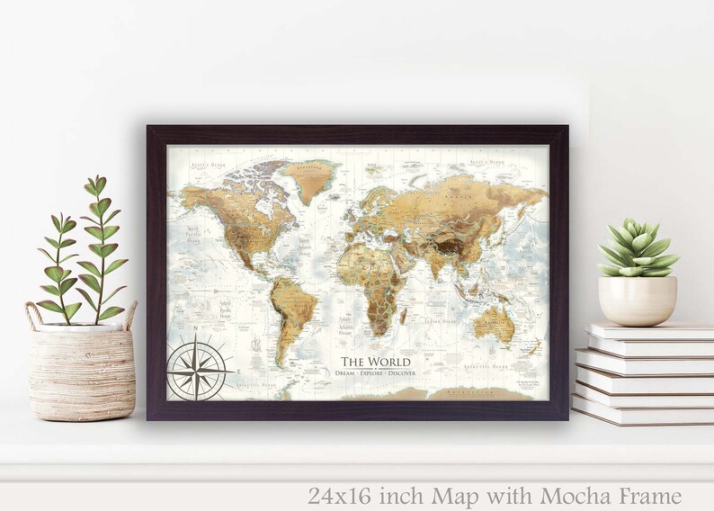 Puede incluir: Un mapa del mundo enmarcado con un marco moca. El mapa est&aacute; impreso sobre un fondo blanco con detalles marrones y beige. El mapa incluye una br&uacute;jula y el texto "The World Dream Explore Discover". El mapa mide 61 cm por 41 cm.