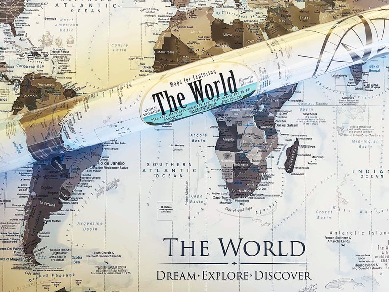 May include: A rolled up world map with a vintage style design. The map is printed on a light blue background with brown and black lines and text. The map is titled "The World" and has the words "Dream Explore Discover" printed below the title.