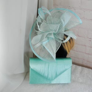 Peut inclure: Une pochette en satin bleu clair et un fascinateur bleu clair assorti avec un grand nœud et des plumes.