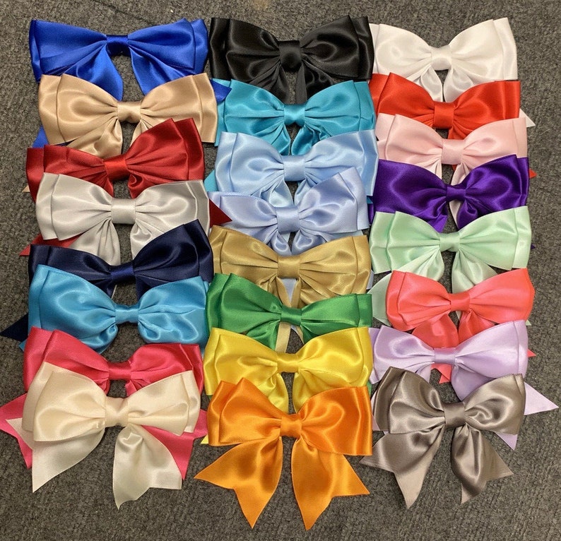 May include: A collection of 15 colorful satin bows with a variety of colors, including blue, red, green, purple, and white.
