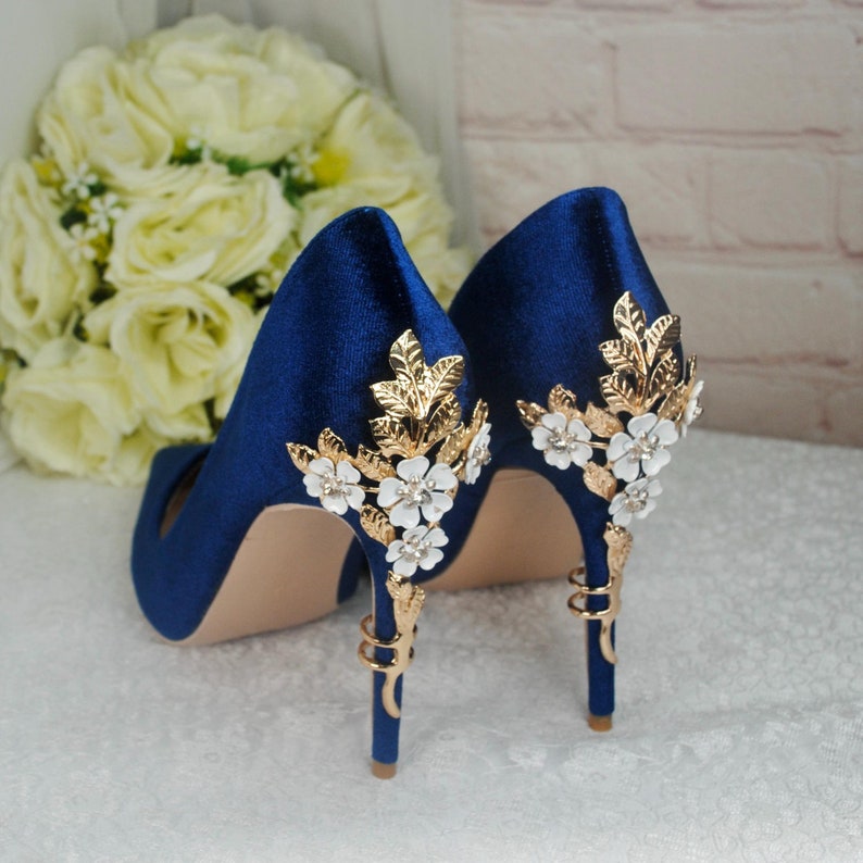 May include: A pair of blue satin high heels with gold and white floral embellishments.