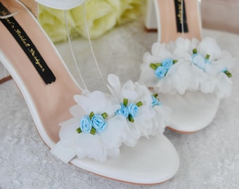 Sandalias blancas de novia con tacón de bloque y detalles florales en rosa azul