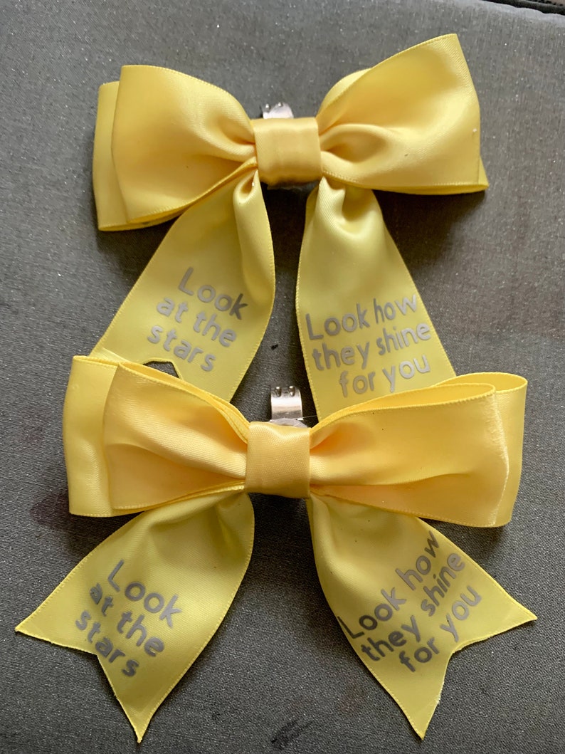 May include: Two yellow satin bows with silver text. The text on the bows reads "Look at the stars" and "Look how they shine for you".