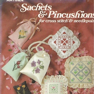 May include: A collection of cross-stitch sachets and pincushions. The image features various designs, including floral patterns and geometric shapes, in soft pastel colors. The text on the image reads "Sachets & Pincushions for cross stitch & needlepoint".