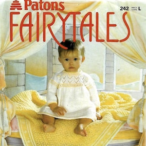 Puede incluir: Un bebé con un vestido de punto blanco y amarillo está sentado sobre una manta amarilla. La imagen es de un libro de patrones Patons Fairytales, con el texto "Veinte hermosos diseños de punto a mano desde el nacimiento hasta los quince meses."
