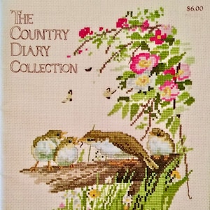 Puede incluir: Patrón de punto de cruz con una familia de pájaros posados en una rama con flores rosas y hojas verdes. El título "The Country Diary Collection" está en la esquina superior izquierda y el precio $ 6.00 está en la esquina superior derecha.