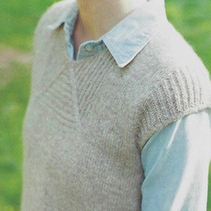 May include: A beige sleeveless knitted sweater with a V-neck and a textured pattern.