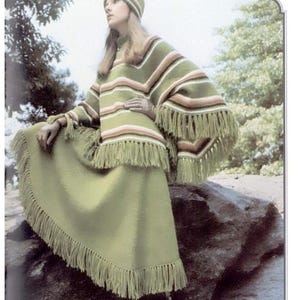 May include: A vintage green knitted outfit comprising a fringed poncho, a matching skirt, and a hat. The poncho features horizontal stripes in white, orange, and brown. The skirt and hat are plain green.