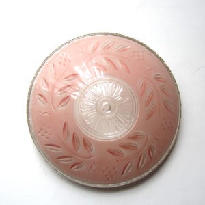 May include: A vintage pink glass ceiling light fixture with a clear glass center. The pink glass shade features an etched leaf and berry design. The fixture has a silver-colored metal rim.