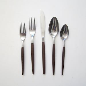 May include: A five-piece flatware set featuring stainless steel heads and dark brown handles. The set includes a small fork, a large fork, a dinner knife, a large spoon, and a small spoon, all arranged vertically against a plain white background.