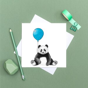 May include: A black and white panda bear sitting with a blue balloon. The panda is smiling and the balloon is tied to its paw.