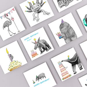 May include: A collection of square birthday cards featuring whimsical animal illustrations. The cards showcase various animals, including an axolotl, aardvark, and anteater, each adorned with party hats and cakes. The phrase "Happy Birthday to you!" is printed on some cards.
