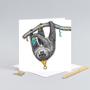 May include: A birthday card featuring a black and white illustration of a sloth wearing a party hat and holding a gift, hanging upside down from a branch with colorful streamers.