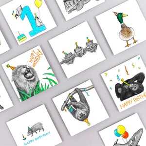 May include: A set of 10 greeting cards featuring various animals wearing party hats. The cards are white with black and white illustrations of a lion, a sloth, a turtle, a duck, a paca, a gorilla, three frogs, and a whale. The cards have the text "Happy Birthday" on them.