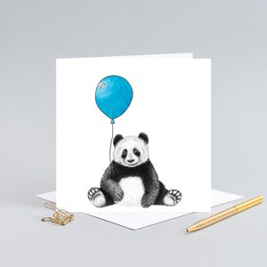 May include: A black and white panda bear sitting with a blue balloon. The panda is holding the string of the balloon in its paws.