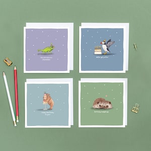Pu&ograve; includere: Quattro biglietti di auguri quadrati con illustrazioni di animali a tema compleanno. Le carte presentano un camaleonte, una pulcinella di mare, un orso e due ricci. Su sfondo verde, con matite e un temperamatite.