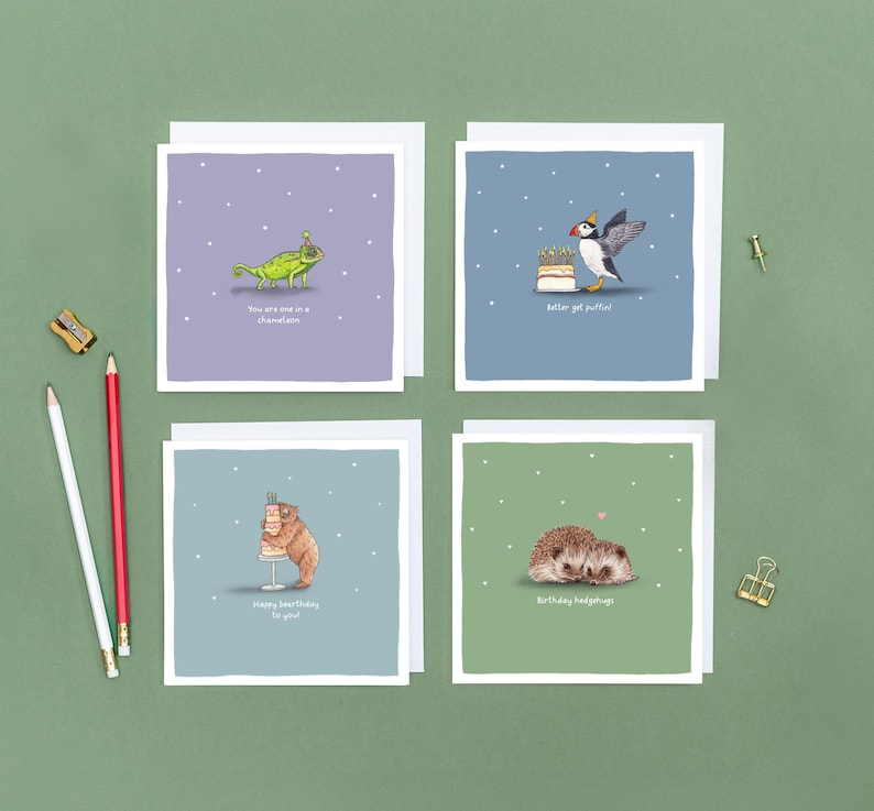 Pu&ograve; includere: Quattro biglietti di auguri quadrati con illustrazioni di animali a tema compleanno. Le carte presentano un camaleonte, una pulcinella di mare, un orso e due ricci. Su sfondo verde, con matite e un temperamatite.