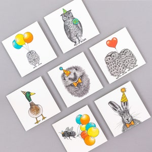 May include: Set of 8 greeting cards featuring various animals wearing party hats and holding balloons. The animals include an owl, a hedgehog, a duck, a rabbit, a bee, and two owls. The cards are blank inside for writing a message.