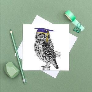 May include: A graduation-themed greeting card featuring a detailed illustration of an owl wearing a purple and gold graduation cap and holding a diploma. The owl is perched on a wooden post. The card is on a white background.