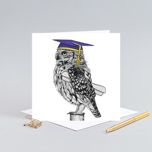 May include: A graduation greeting card featuring a detailed black and white illustration of an owl wearing a purple graduation cap and holding a diploma. The owl is perched on a wooden post. A gold pen and paperclip are in the background.