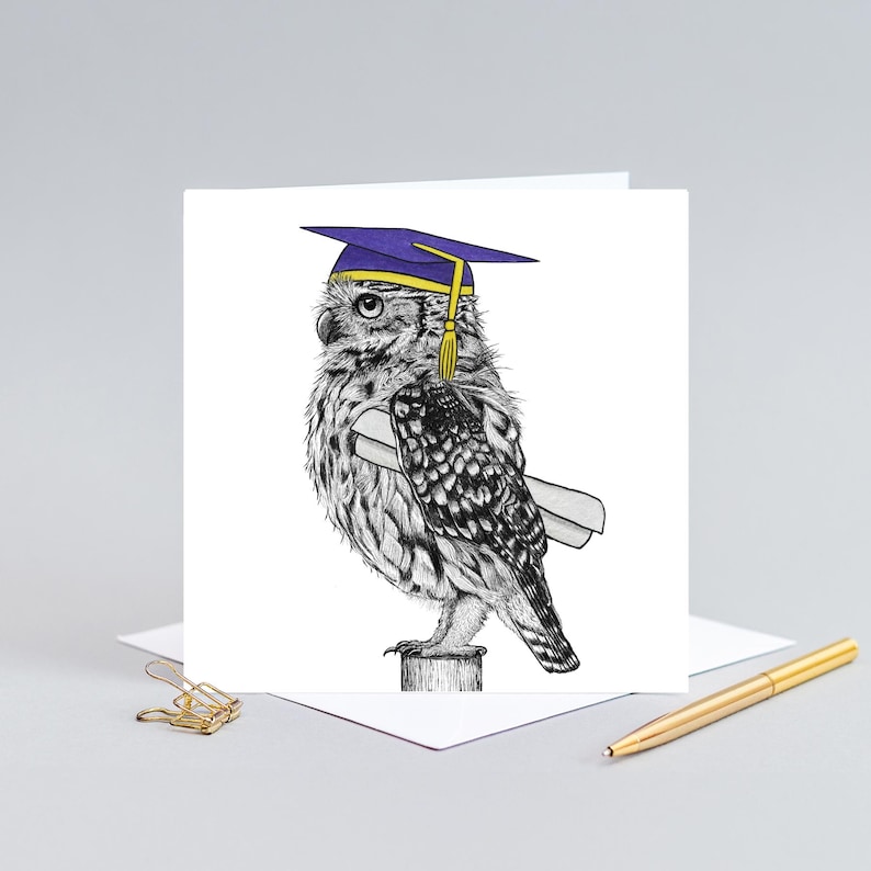 May include: A graduation greeting card featuring a detailed black and white illustration of an owl wearing a purple graduation cap and holding a diploma. The owl is perched on a wooden post. A gold pen and paperclip are in the background.