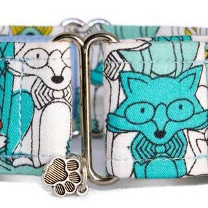 Puede incluir: Un collar para perro turquesa y blanco con un estampado de zorro caprichoso. El collar tiene una hebilla plateada y un amuleto plateado con una huella de pata. El collar está hecho por "Knoddy & Sweets handmade petgear".