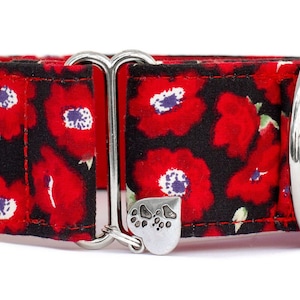 May include: Red and black floral dog collar with a silver buckle and a heart-shaped charm with a paw print. The collar has the text "Kody & Sweets Handmade Petgear" on it.
