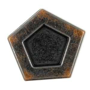 Puede incluir: Un objeto de metal en forma de estrella de cinco puntas con una estrella de cinco puntas más pequeña y hundida en el centro. La estrella exterior es de color cobre con una pátina marrón oscura, mientras que la estrella interior es negra.