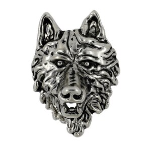 Puede incluir: Un colgante de cabeza de lobo de plata con un diseño detallado y texturizado. La boca del lobo está abierta, mostrando sus dientes.