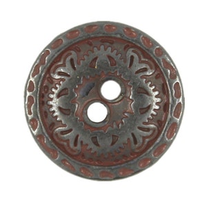 Könnte beinhalten: Ein Knopf mit zwei Löchern, silberfarbenem Metallgrund und rotbraunem Rand. Der Knopf hat ein dekoratives Design mit einem floralen Muster.